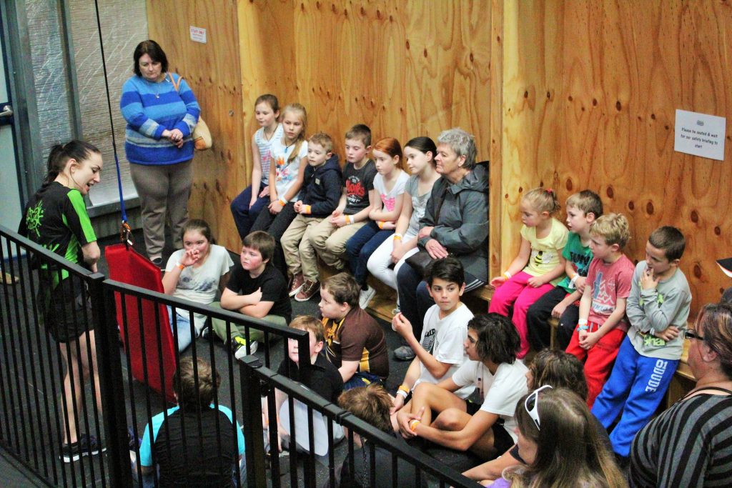 A group of school-age children listening to a Jump & Climb safety briefing